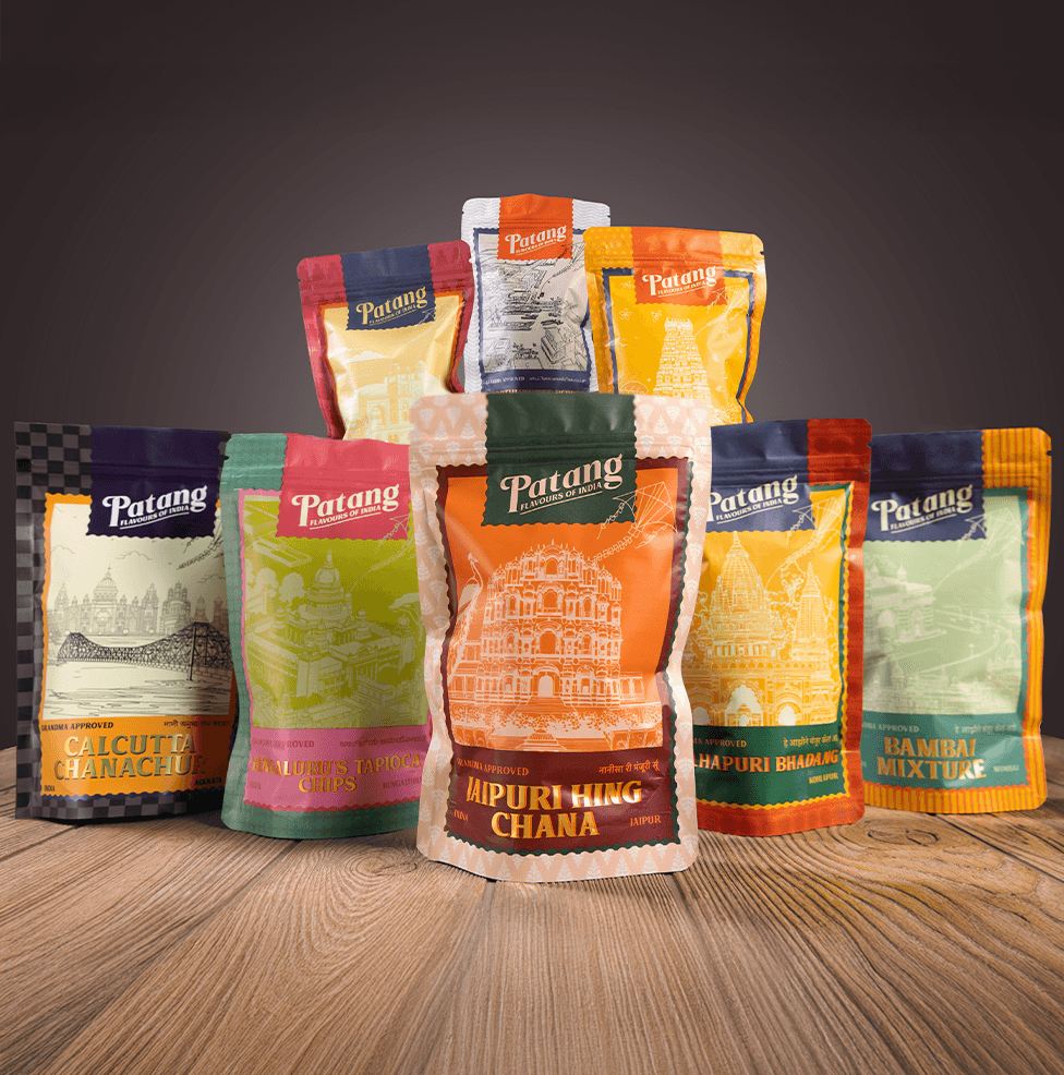 Collection of Patang brand food packaging on a wooden surface with a dark background