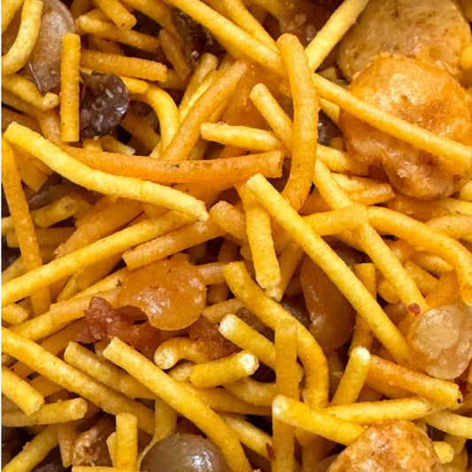 Close-up of a snack mix with yellow and orange sev and dal.