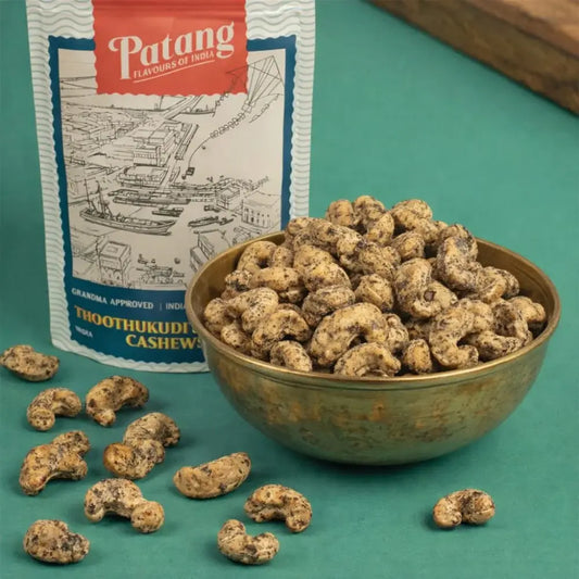 Bowl of cashews with Patang Thoothukudi Cashew packaging on a teal background