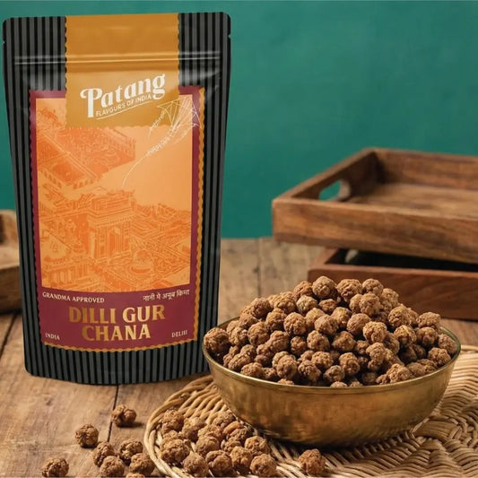 Patang Dilli Gurchana packaging with a bowl of gurchana on a wooden surface.