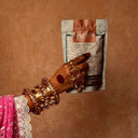 Hand holding a Patang product against a brown background