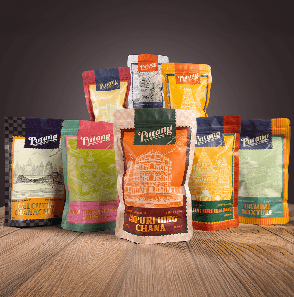 Collection of Patang brand food packaging on a wooden surface with a dark background