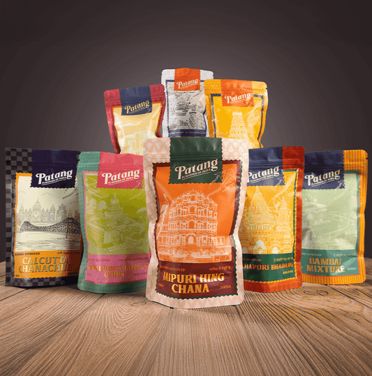 Collection of Patang brand food packaging on a wooden surface with a dark background