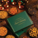 Green gift box with 'For Every Moment Worth Cherishing' text on a wooden table with Diwali snacks.