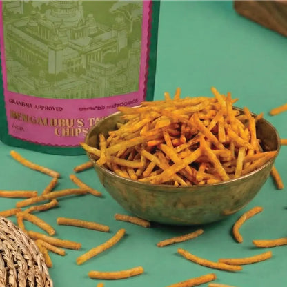 Bowl of chips with a packaging box labeled Bengaluru's Tapioca Chips on a teal background