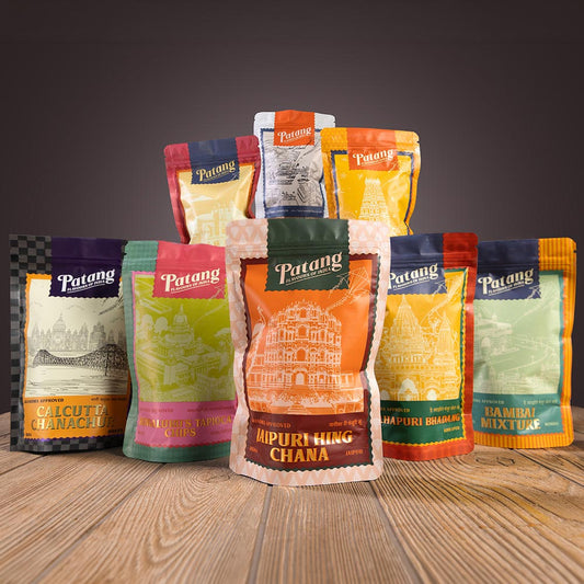 Collection of Patang brand food packages on a wooden surface with a dark background